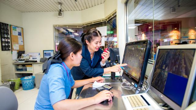 An employee at a railway company in Thailand consults with a colleague in front of a computer. 