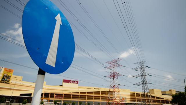 A street sign with an arrow pointing upward is seen in the foreground with electric lines and posts seen in the background.