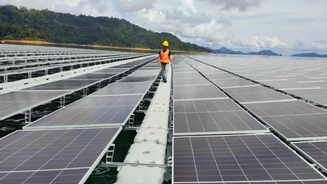 A worker walks across a field of floating solar panels in a solar farm in Sarawak.