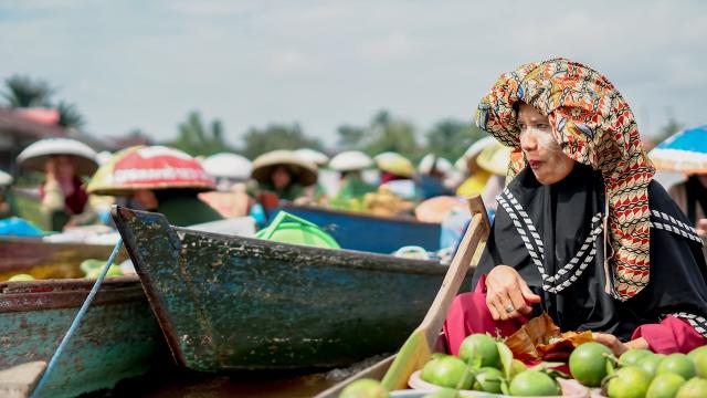 A woman on a boat at a floating market in Kalimantan. Photo credit: iStock/Adennysyahputra.