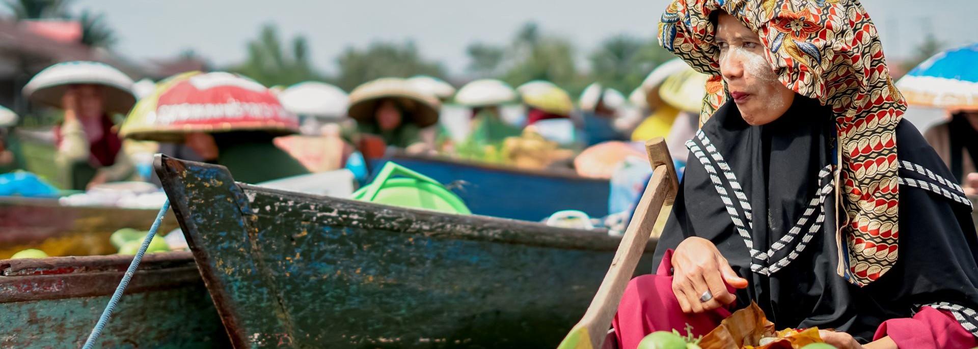 Floating market seller paddling a boat to Lok Baintan floating market, South Kalimantan. Photo credit: iStock.